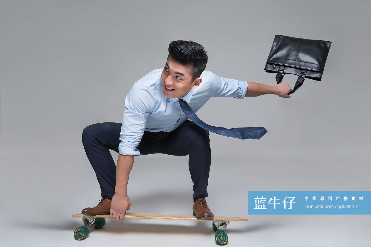 快乐的年轻商务男子拎着公文包滑滑板