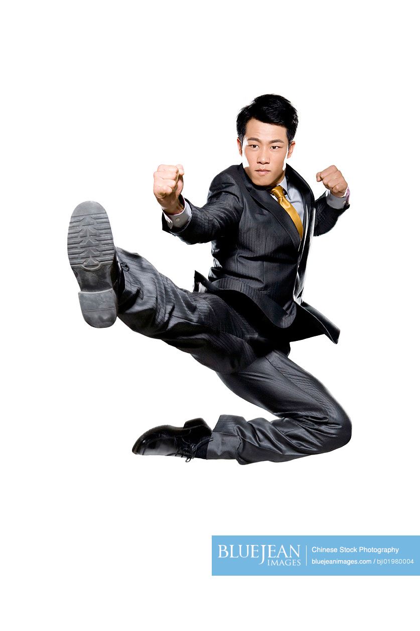 Chinese businessman in martial arts position mid-air