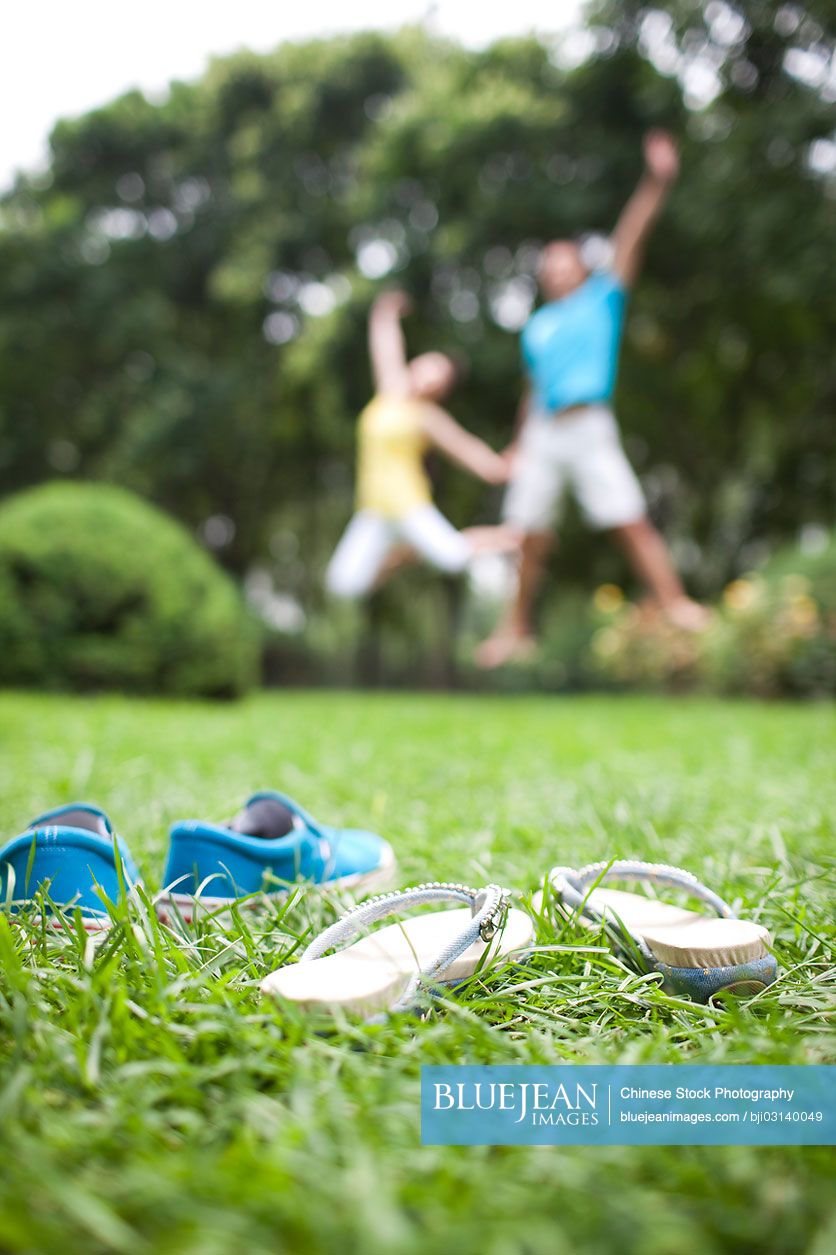 Excited Chinese couple jumping on meadow