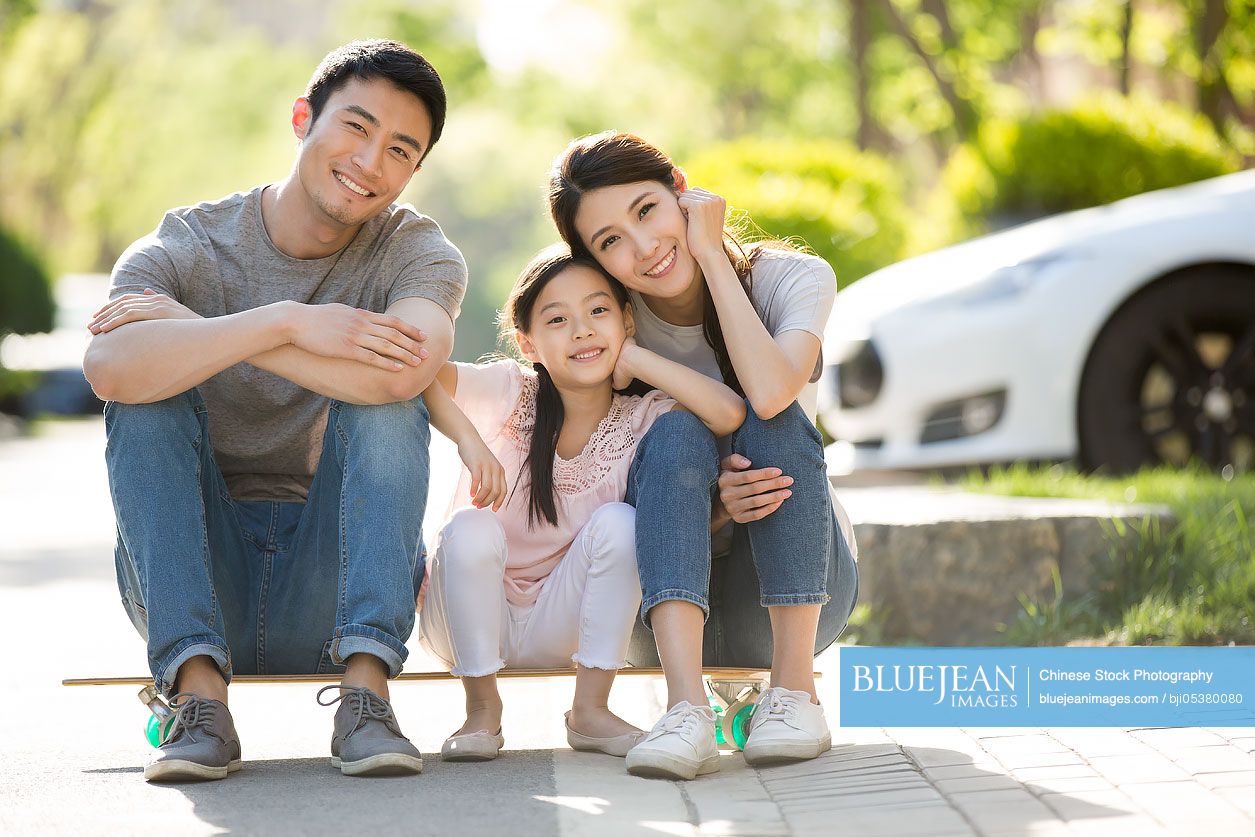 Happy young Chinese family sitting on a skateboard