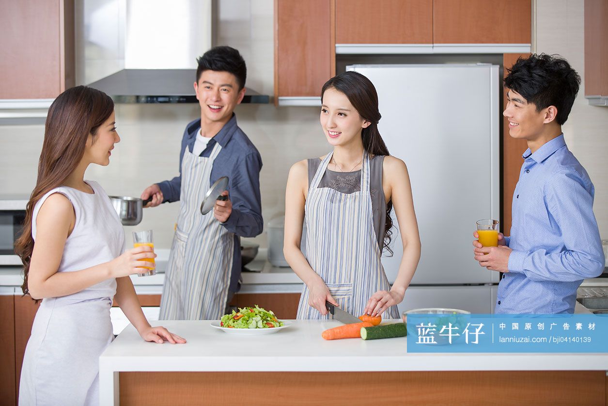年轻情侣在厨房边做饭边和朋友聊天