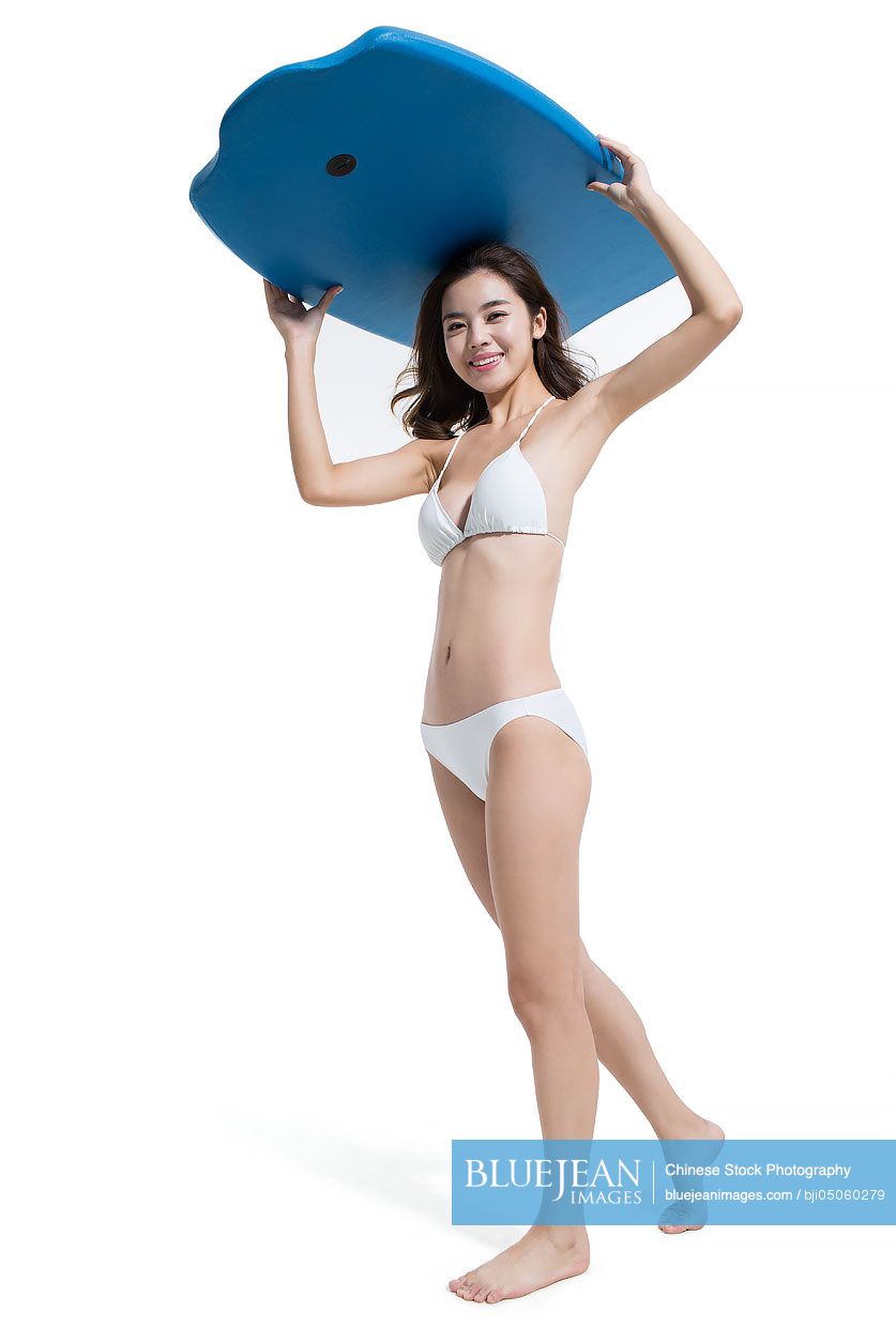 Beautiful young Chinese woman in bikini with surfboard
