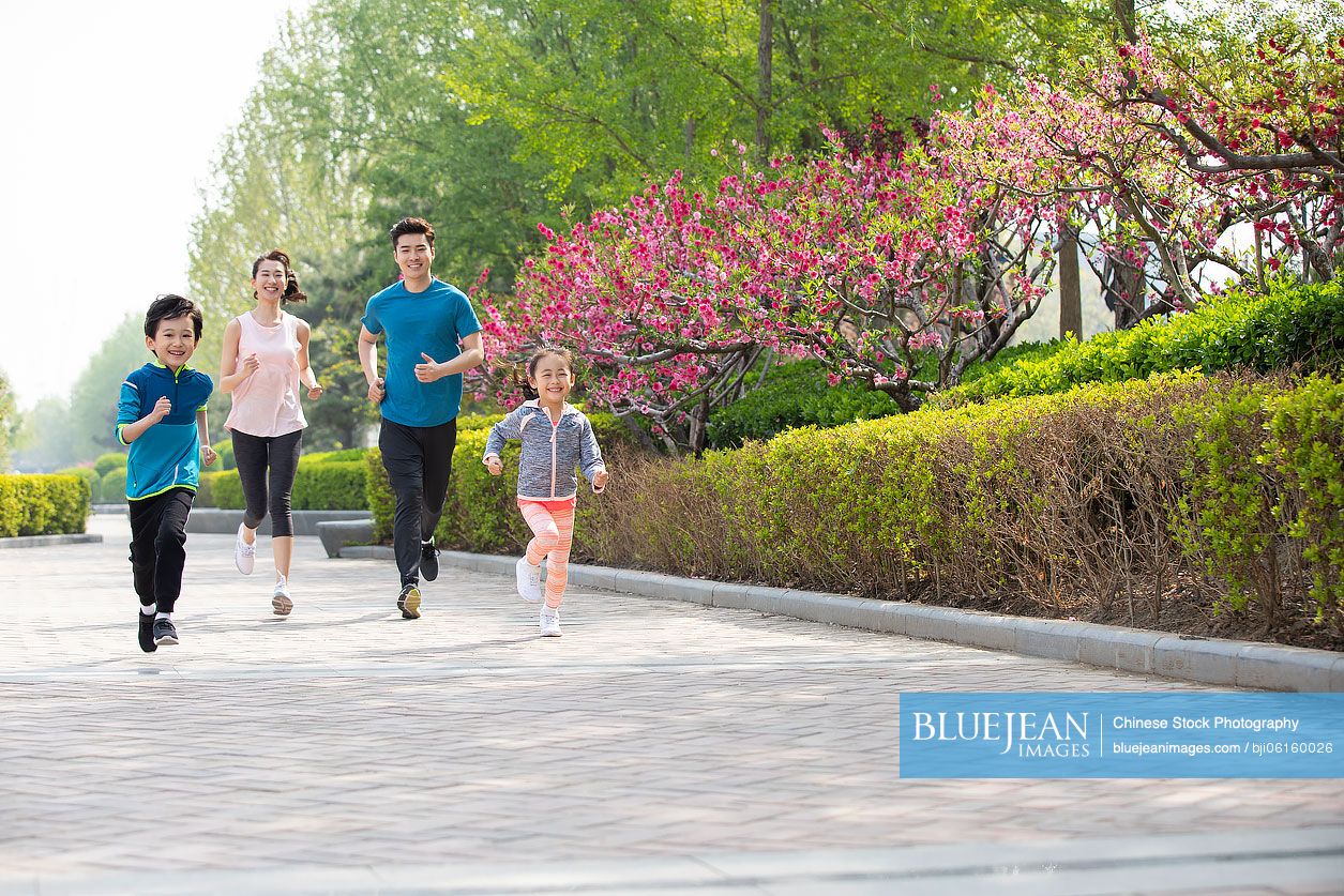 Happy young Chinese family running in park