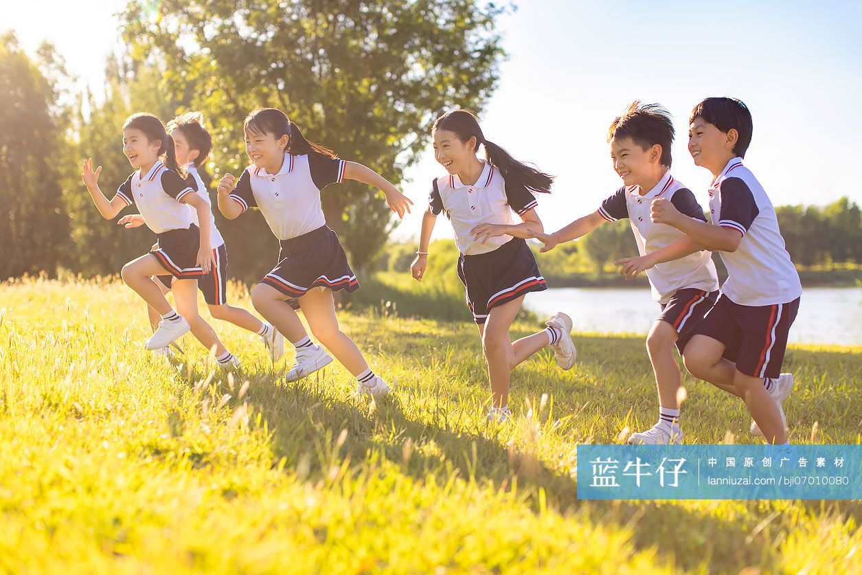 快乐的小学生在草地上奔跑