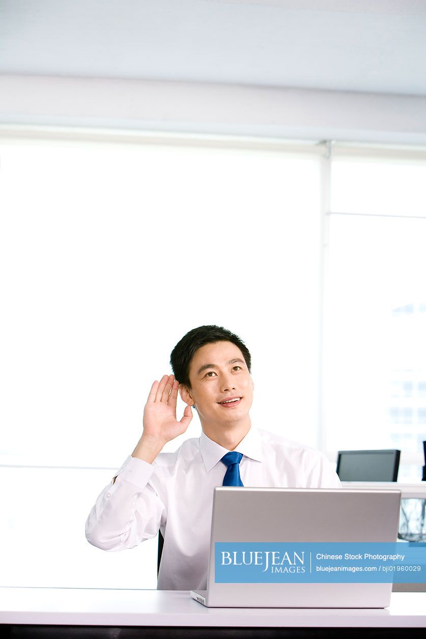 Happy Chinese office worker at his desk