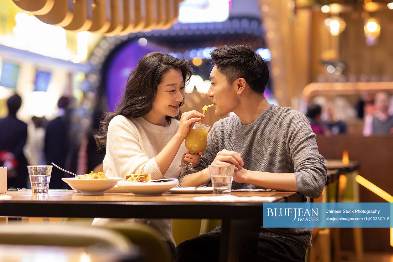 Happy young Chinese couple dating in restaurant
