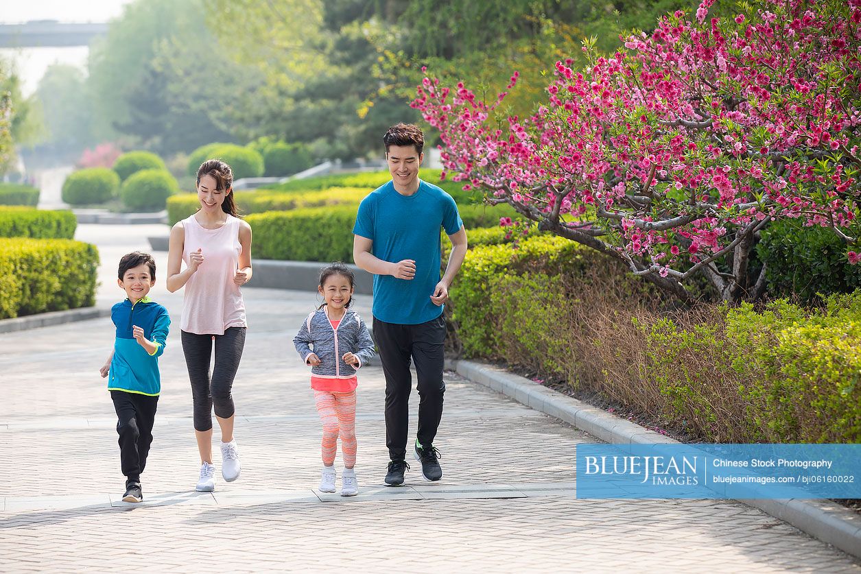 Happy young Chinese family running in park