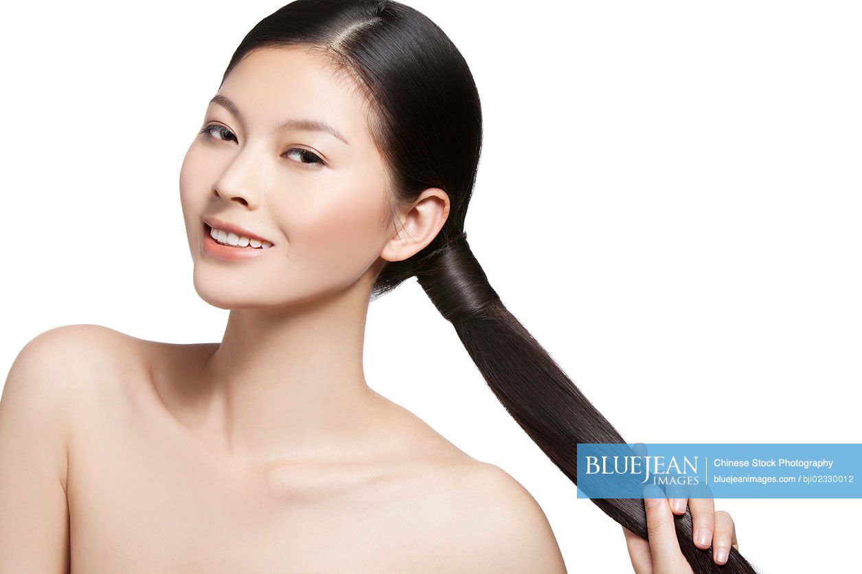 Young Chinese woman holding silky long ponytail