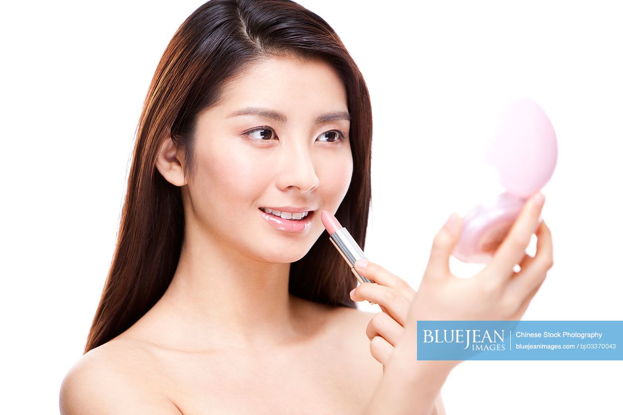 Pretty young Chinese woman applying cosmetics