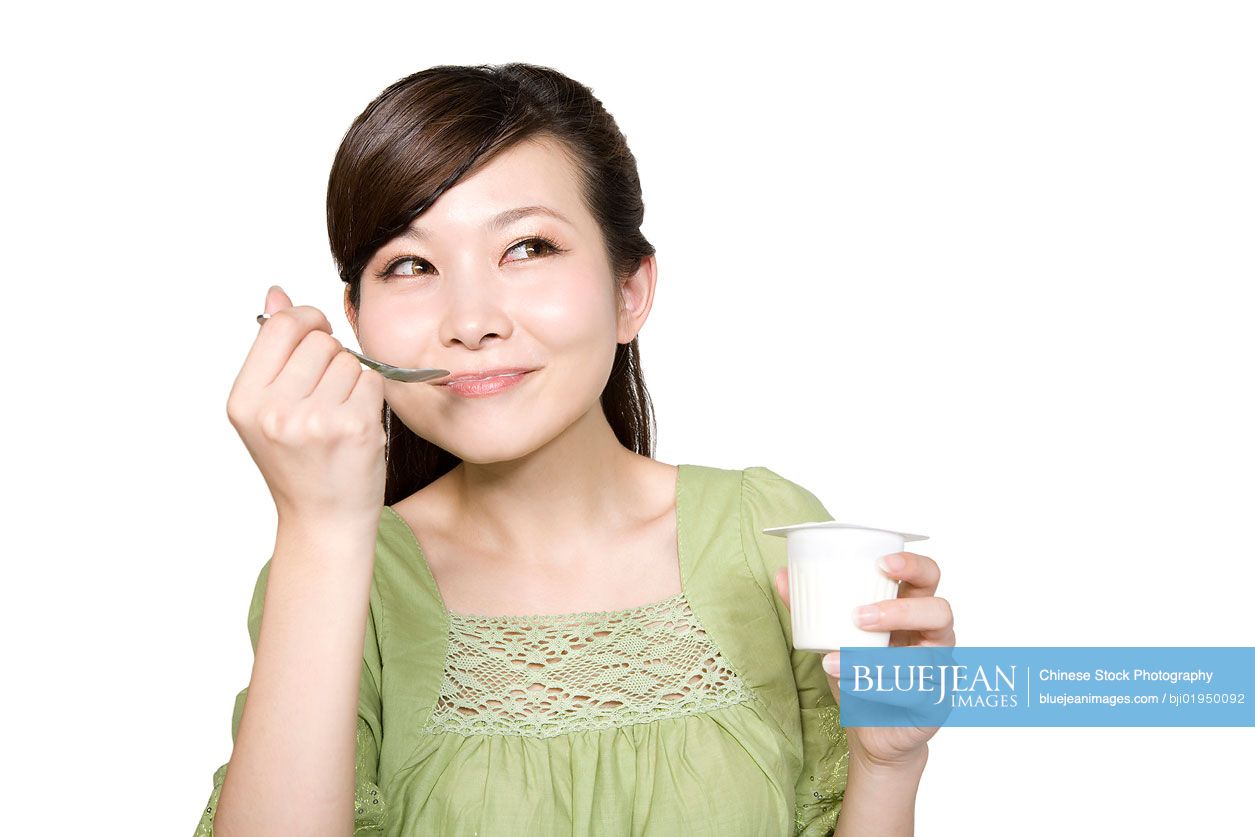 Portrait of young Chinese woman eating yogurt