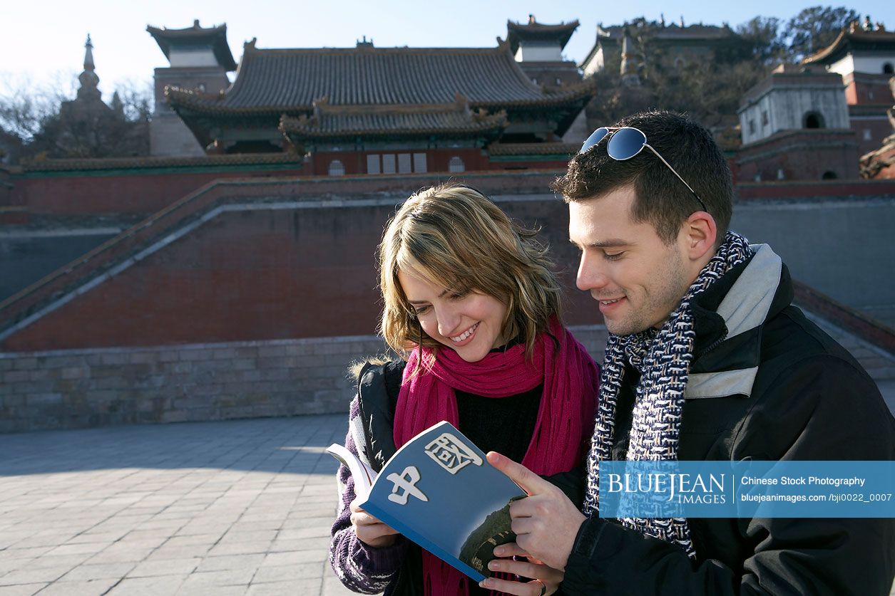 Young couple visiting the Chinese Forbidden City looking at guide book