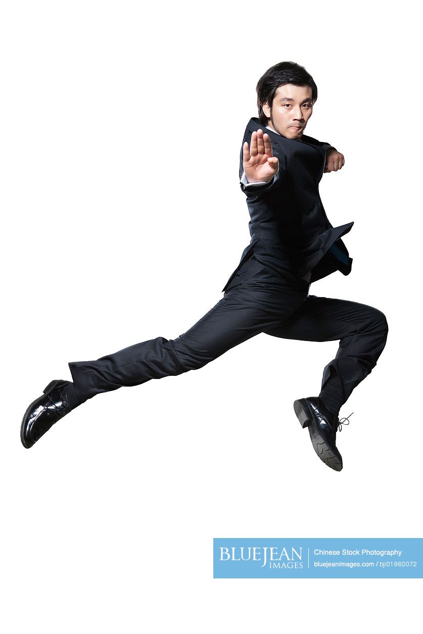 Chinese businessman in martial arts pose mid-air