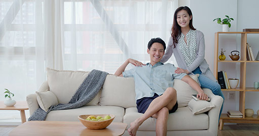 Happy young Chinese couple sitting on sofa,4K