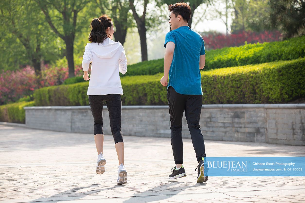 Happy young Chinese couple running in park