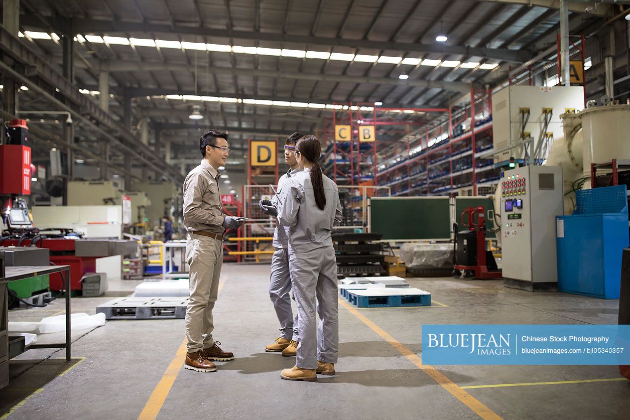 Confident Chinese engineers talking in the factory