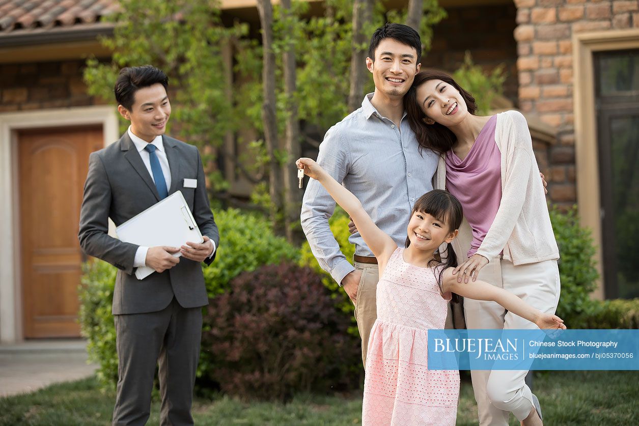 Happy young Chinese family holding keys to new house