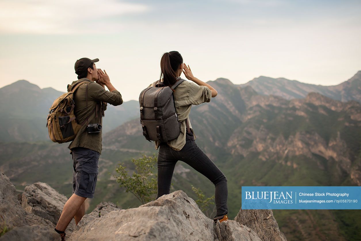 Young Chinese couple shouting on mountain peak