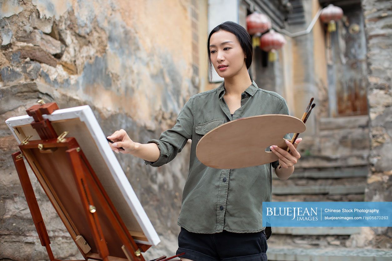 Young Chinese artist painting outdoors