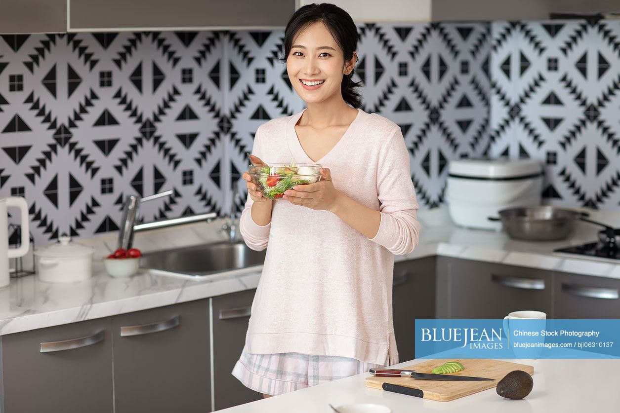 Young Chinese woman cooking in kitchen