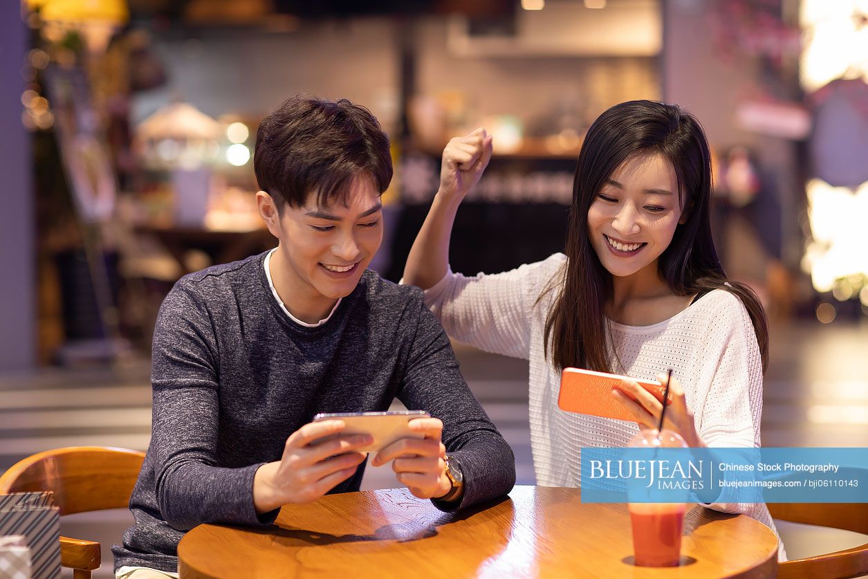 Happy young Chinese couple playing mobile games