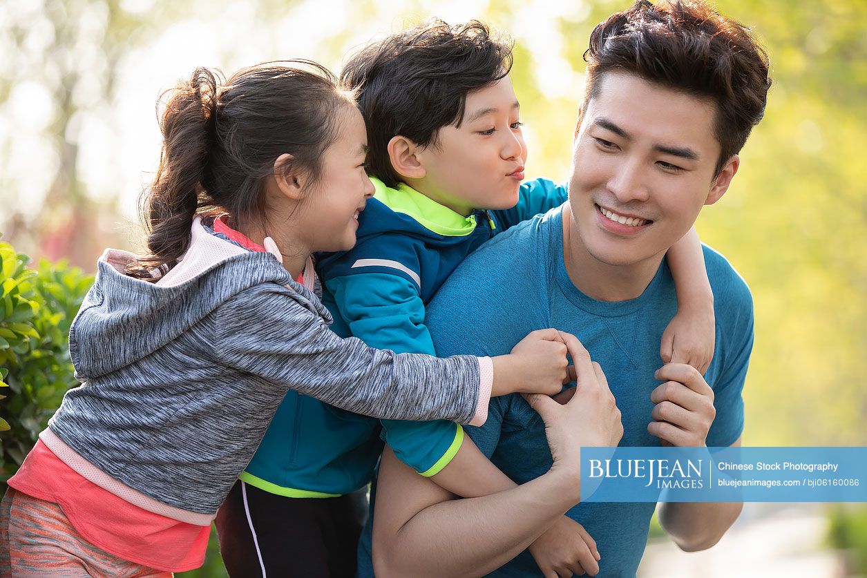 Happy young Chinese family playing in park