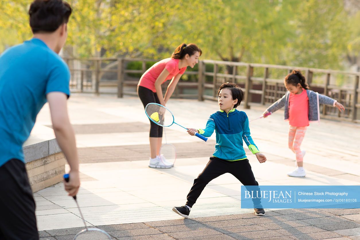 Happy young Chinese family playing badminton in park