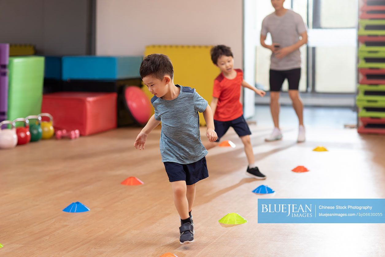 Cute Chinese children having exercise class in gym