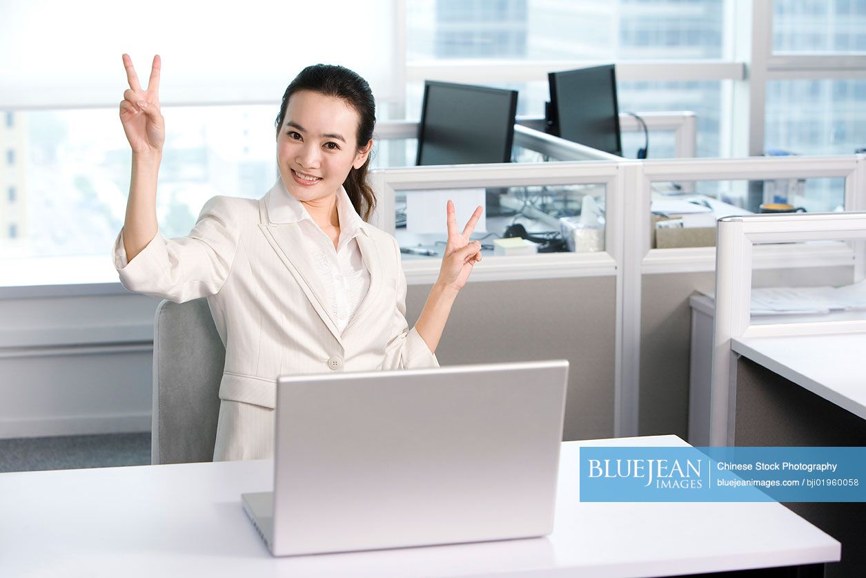 Happy Chinese office worker at her desk