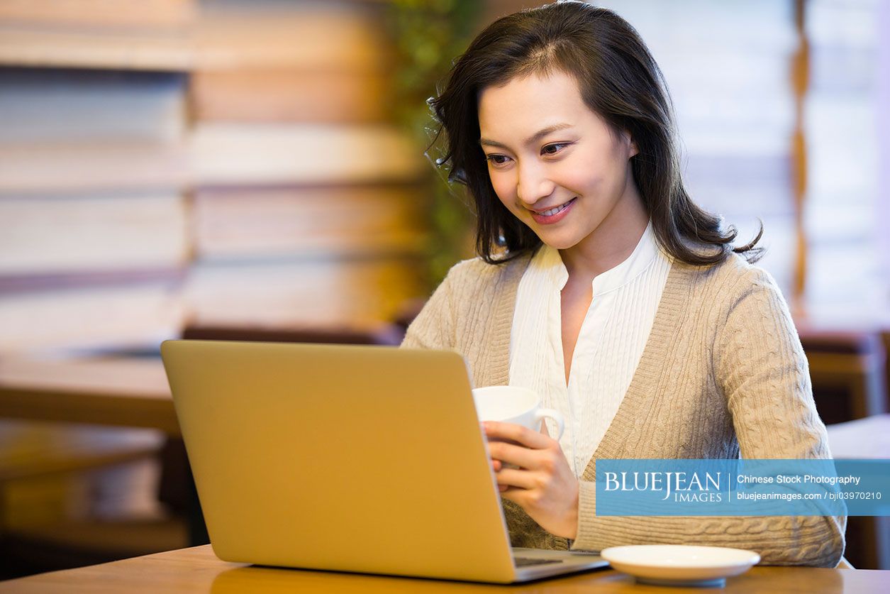 Young Chinese woman using laptop in cafe