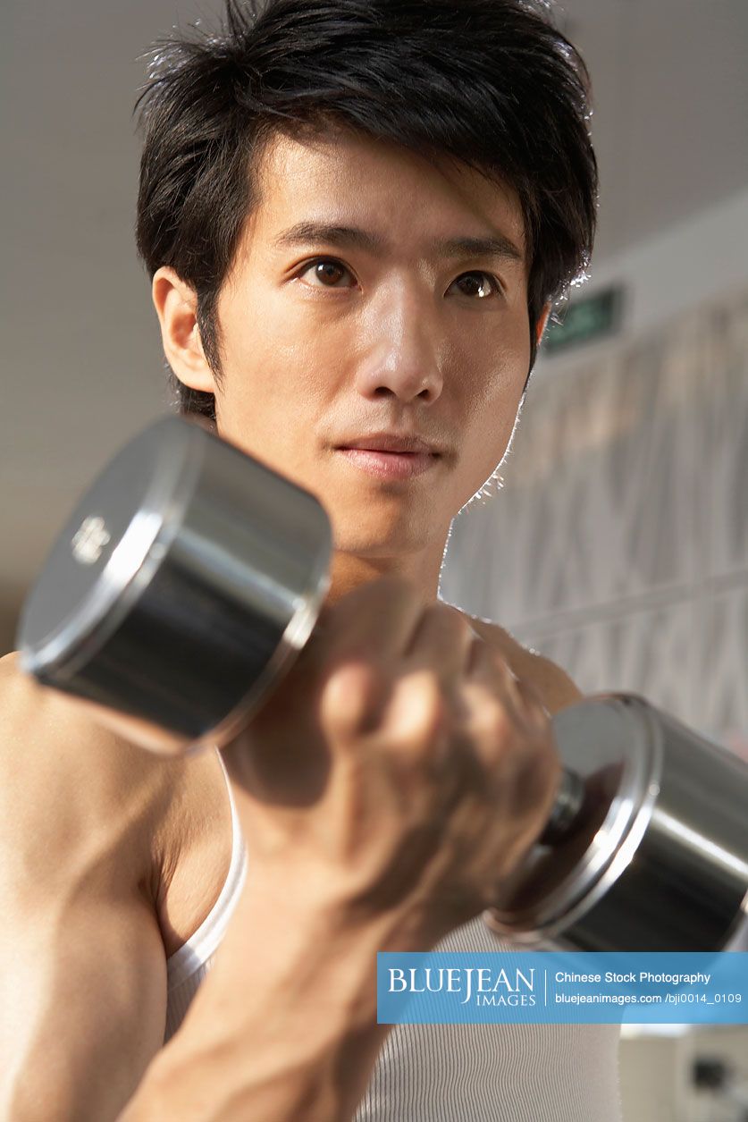 Chinese man lifting weights in gym