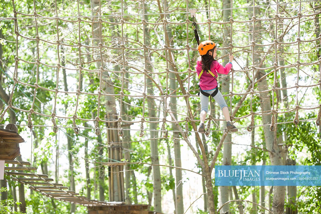 Little Chinese girl playing in tree top adventure park