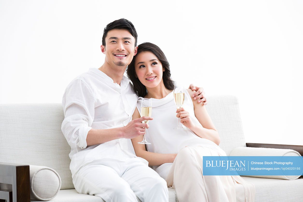 Cheerful young Chinese couple with champagne