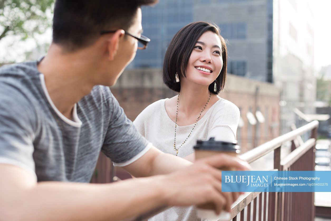 Cheerful young Chinese couple talking outdoors