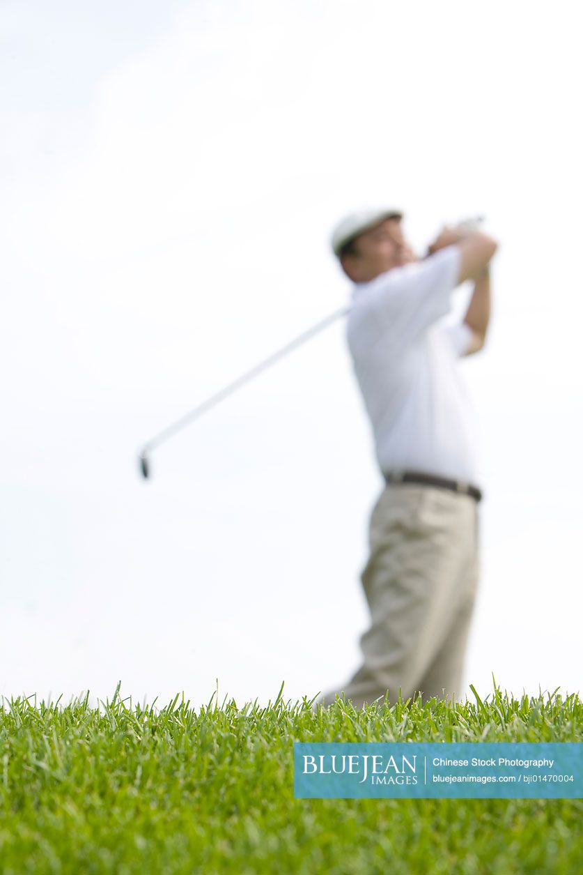 Side view of Chinese golfer's swing, selective focus