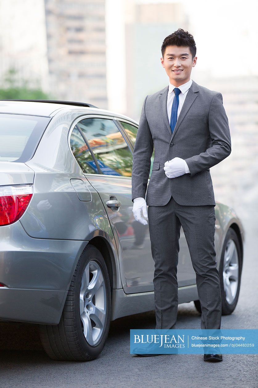 Portrait of Chinese chauffeur standing next to the car