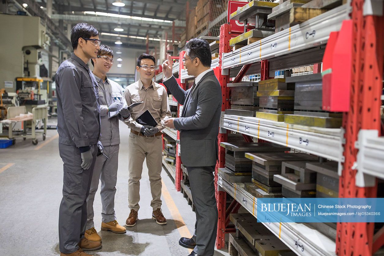 Chinese businessman and engineers talking in the factory