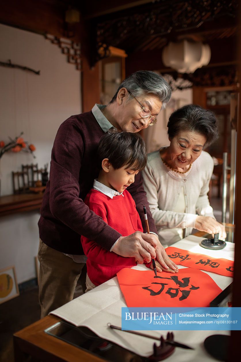 Happy Chinese family writing calligraphy on couplets