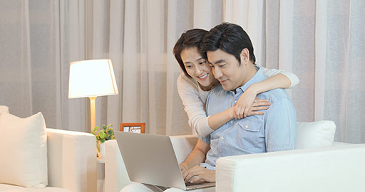 快乐的年轻情侣在客厅使用笔记本电脑