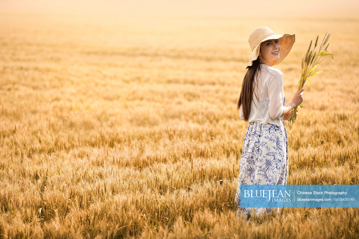 Happy young Chinese woman in wheat field