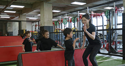 Active Chinese children having exercise class with their coach in gym,4K