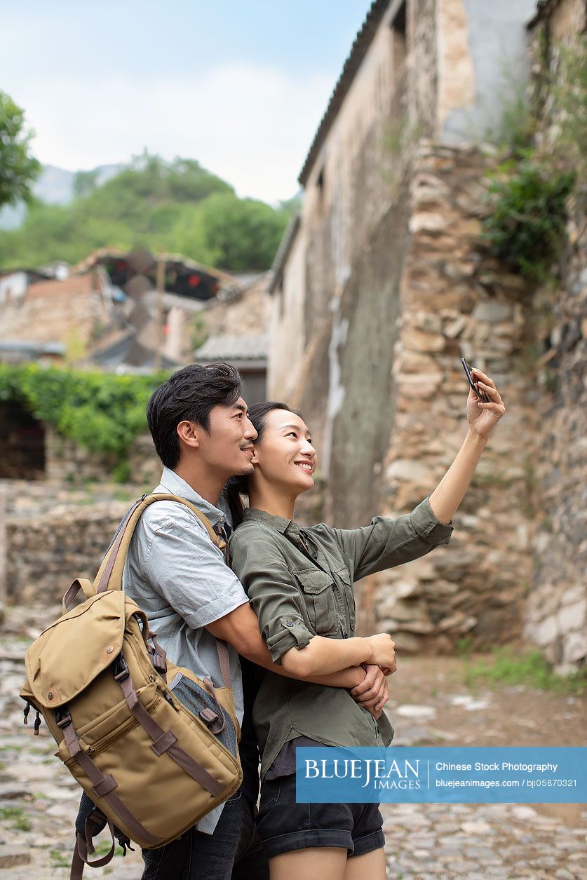 Young Chinese couple taking selfie with smartphone in village