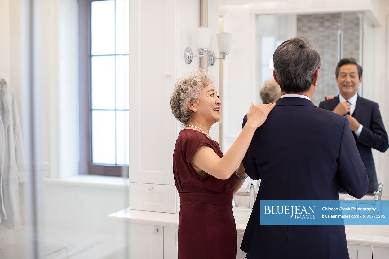 Happy senior Chinese couple getting dressed in bathroom