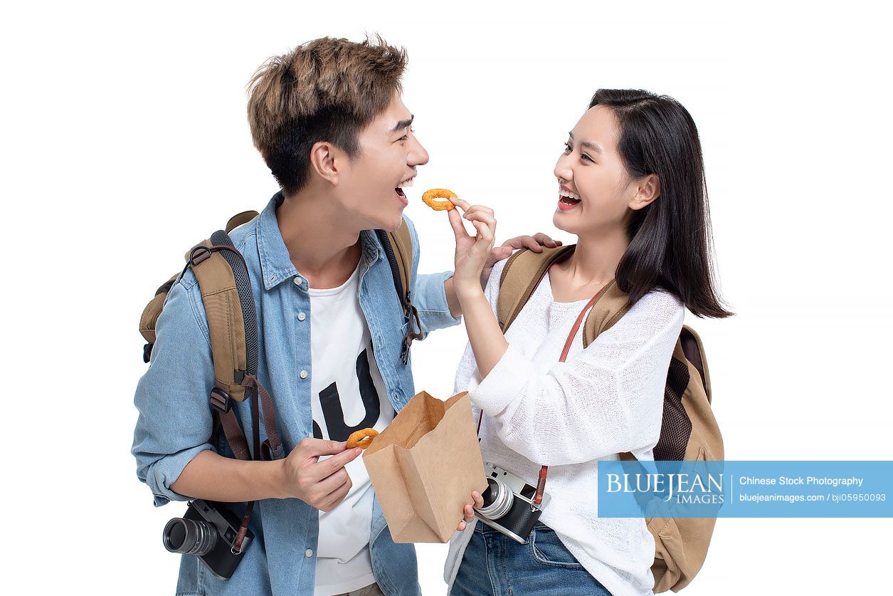 Happy young Chinese couple sharing snack