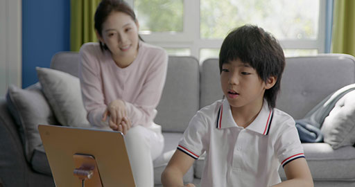 Little boy taking an online class with her mom keeping her company