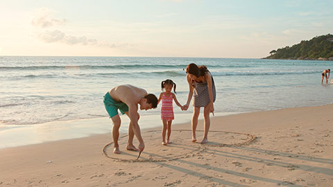 快乐的年轻家庭在沙滩玩耍