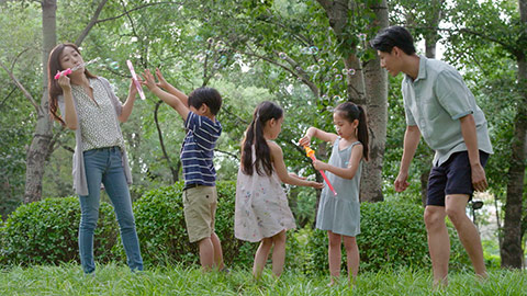 Happy young Chinese family blowing bubbles on grass,HD