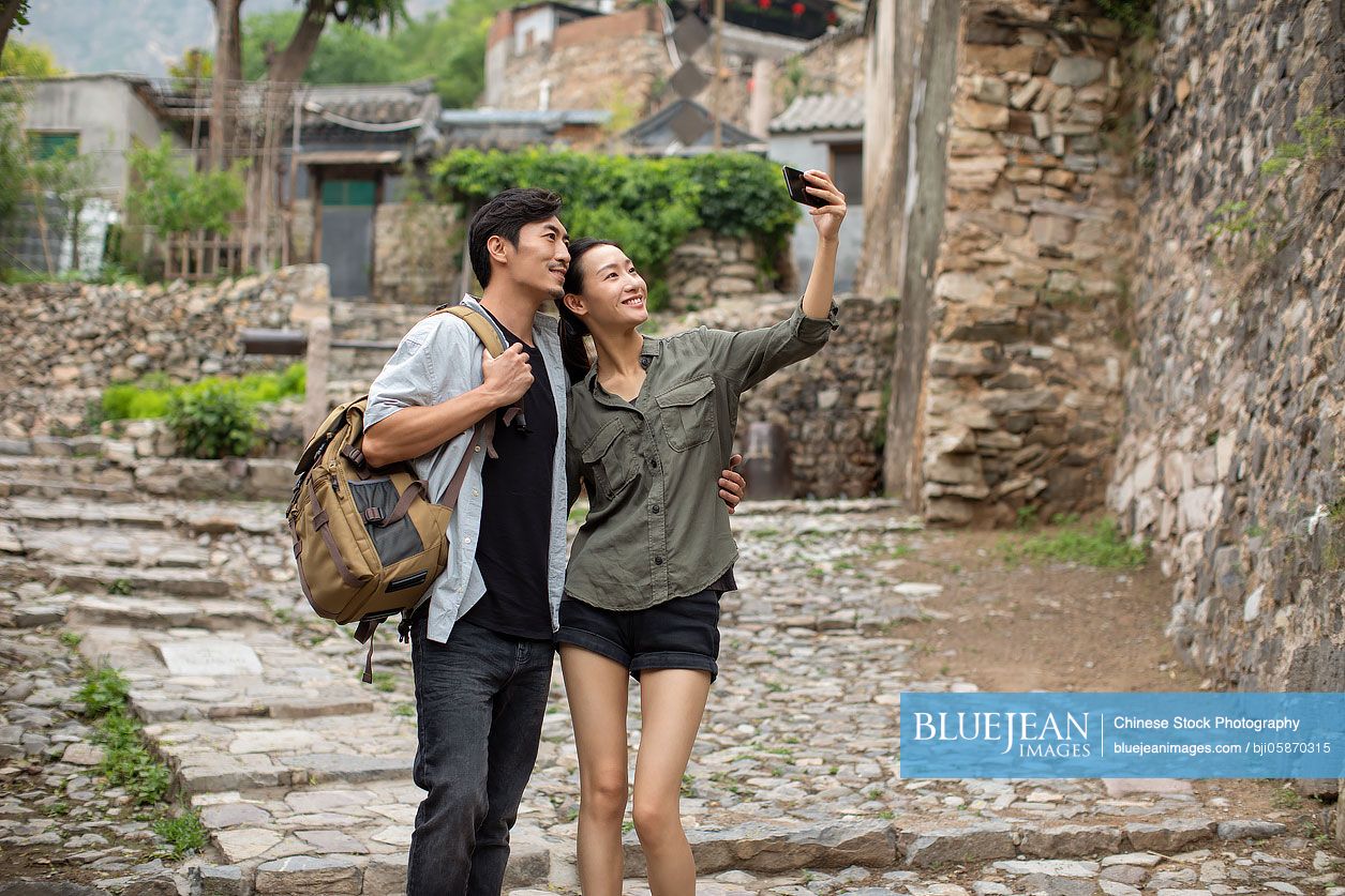 Young Chinese couple taking selfie with smartphone in village