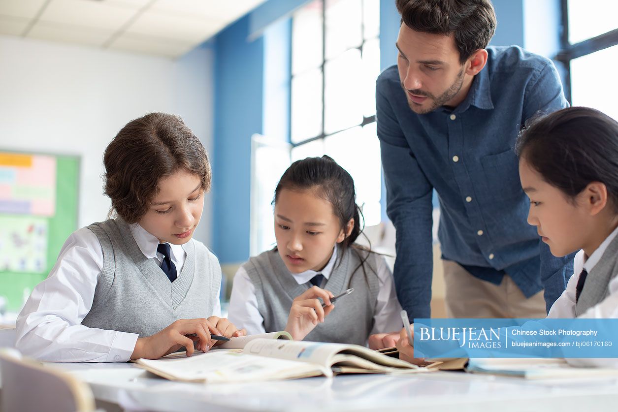 Young teacher helping students in classroom