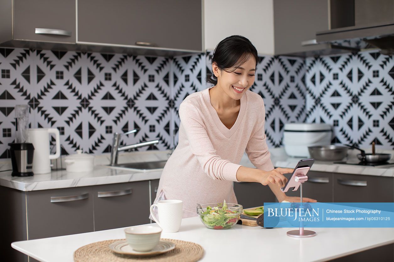 Happy young Chinese woman cooking in kitchen