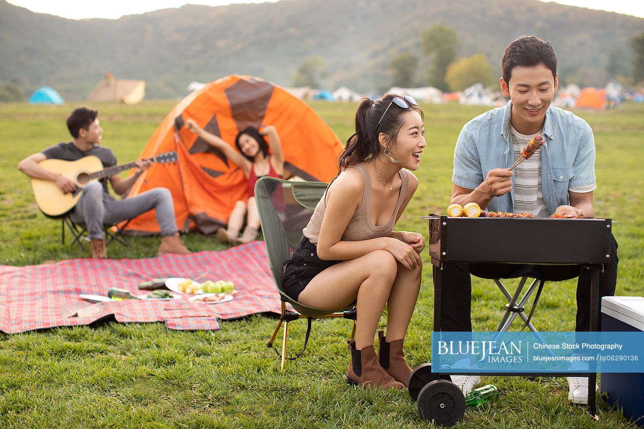 Happy young Chinese friends barbecuing outdoors